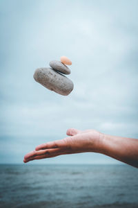 Close-up of hand holding umbrella in sea against sky