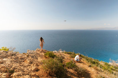 A young couple films a video with a drone near the sea.