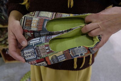 Midsection of woman holding shoes while standing outdoors