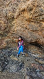 Portrait of woman with arms raised on rock