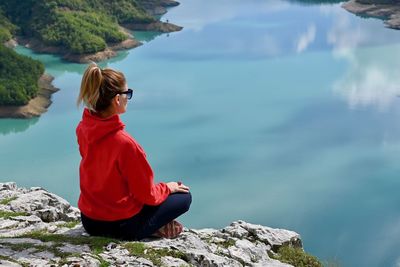 Woman sitting on rock looking at lake