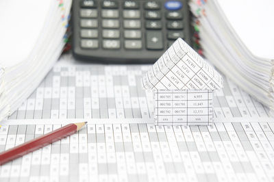 High angle view of model house with calculator and pencil on financial documents