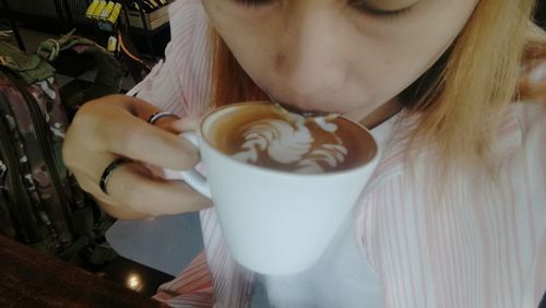 Close-up of woman drinking coffee at cafe