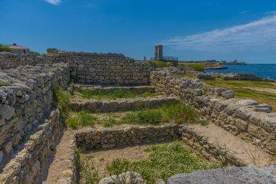 View of old ruin by sea against blue sky