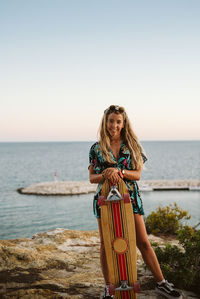 Young woman standing against sea against clear sky