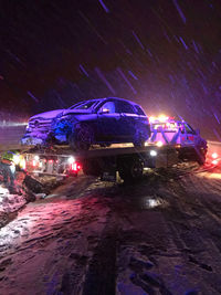 Illuminated road on snow covered field at night