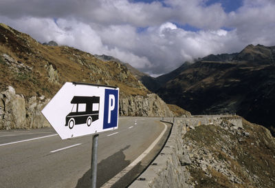 Road sign by mountains against sky