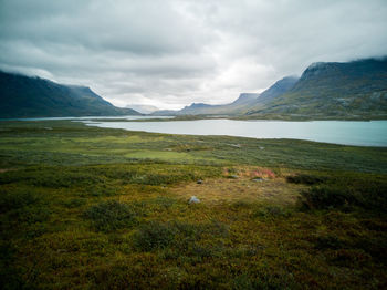 Scenic view of landscape and mountains against cloudy sky