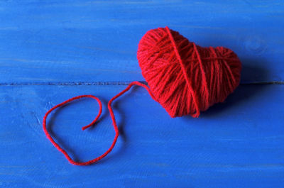 Close-up of heart shape wool ball on blue table