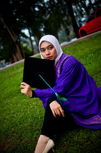 Portrait of beautiful young woman lying on field
