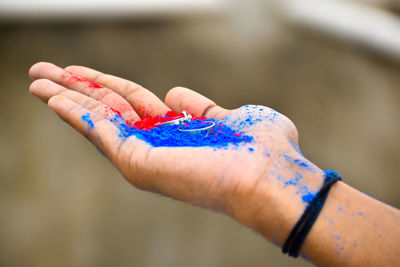 Cropped hand of woman holding powder paint with ring outdoors