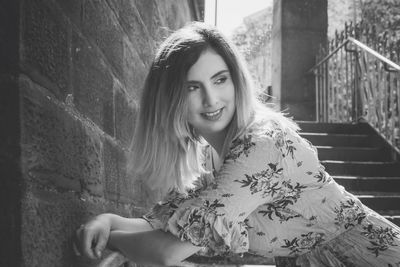 Portrait of smiling woman sitting on staircase