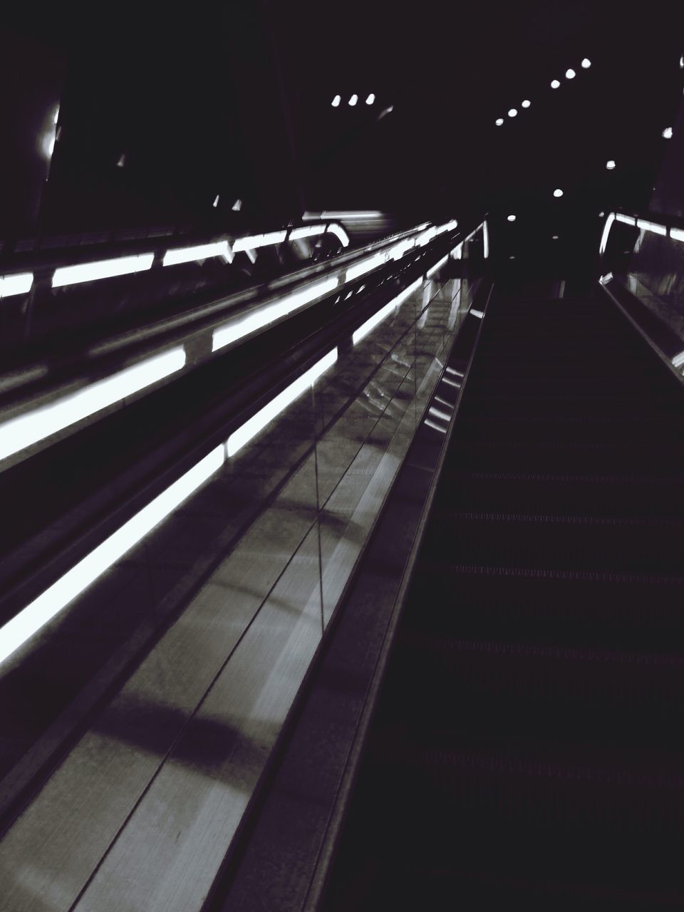 illuminated, transportation, railroad station platform, railroad track, railroad station, rail transportation, night, public transportation, the way forward, indoors, escalator, diminishing perspective, subway station, high angle view, mode of transport, on the move, subway, travel, motion, railing