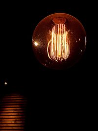 Low angle view of illuminated light bulb against black background