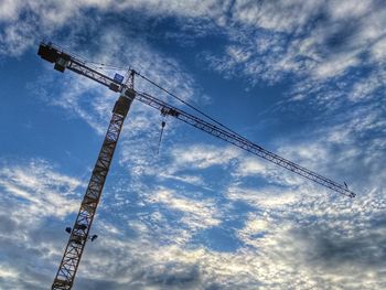 Low angle view of crane against cloudy sky