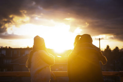 Two women looking at sunset from top of building in vancouver, bc