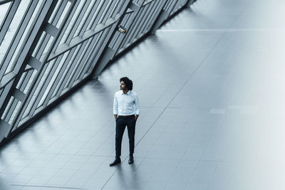 Full length of young woman standing against building