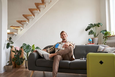 Young woman using mobile phone while sitting on sofa at home