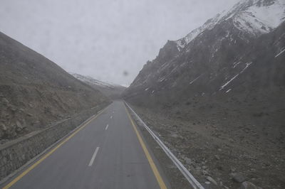 Road amidst mountains against sky during winter