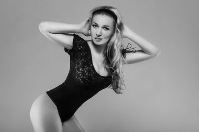 Portrait of beautiful model standing in bodysuit against gray background