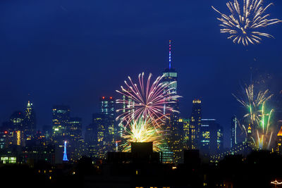 Firework display over illuminated buildings in city at night