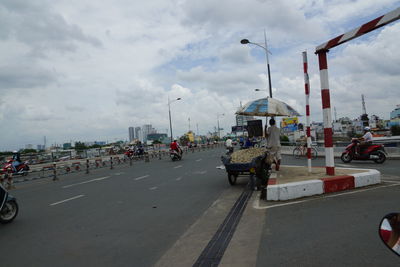 Cars on road against cloudy sky