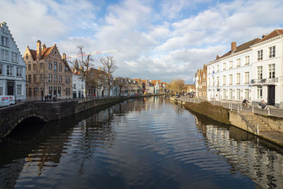 Canal by buildings against sky in city