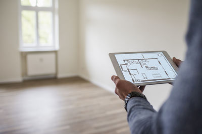 Man in new home holding tablet with floor plan