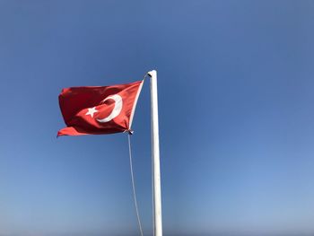 Low angle view of turkish flag against blue sky