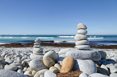 Stack of pebbles on beach against clear blue sky