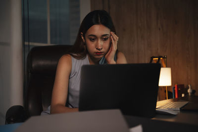 Depressed girl using laptop sitting at home