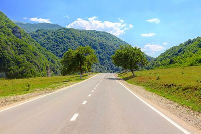 Road leading towards mountains against sky