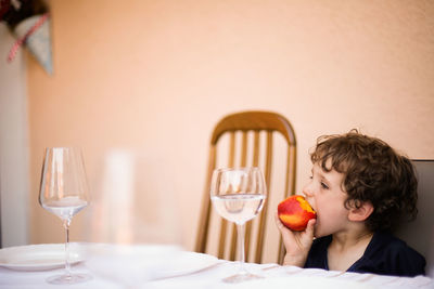 A young boy eating a peach outside during the summer