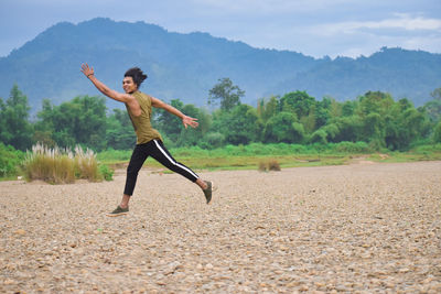 Full length of man jumping on field against sky