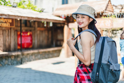 Portrait of smiling young woman against built structure