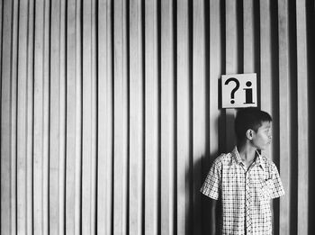 Front view of boy standing against wall