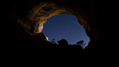 Low angle view of silhouette rock formation against sky at night