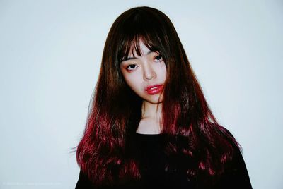 Portrait of young woman against white background