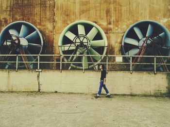 Full length of man walking against electric fans on industry