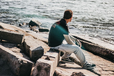 Rear view of man sitting on beach