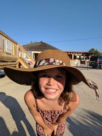 Portrait of smiling girl wearing hat against clear sky
