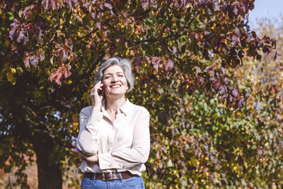 Portrait of a smiling young woman standing against plants