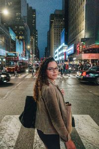 Portrait of woman crossing street in city at night