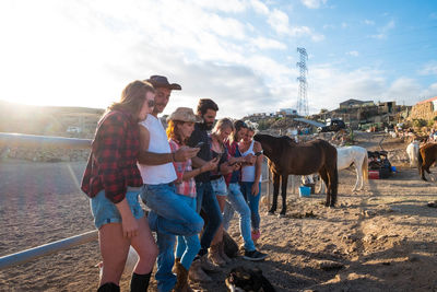 Friends using phones while standing at ranch