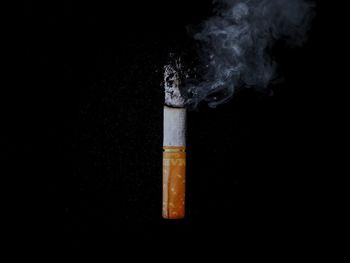 Close-up of cigarette smoking against black background