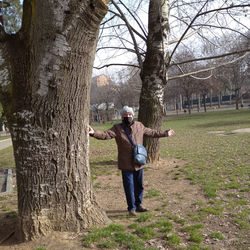 Rear view of man standing by tree trunk