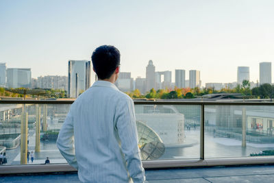 Rear view of man standing against river