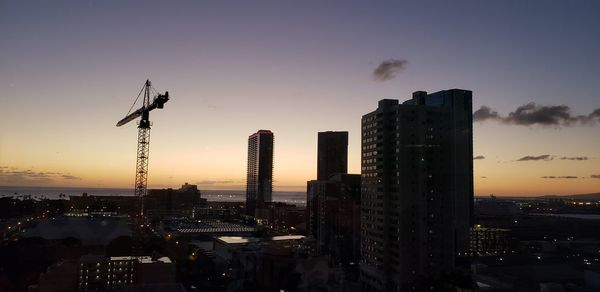 Modern buildings in city against sky during sunset