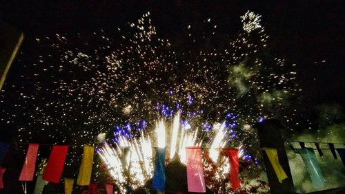 Low angle view of illuminated fireworks against sky at night