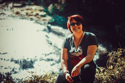 Young woman wearing sunglasses sitting on land